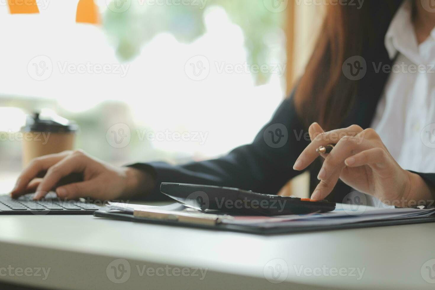 Asian Business woman using calculator and laptop for doing math finance on an office desk, tax, report, accounting, statistics, and analytical research concept photo