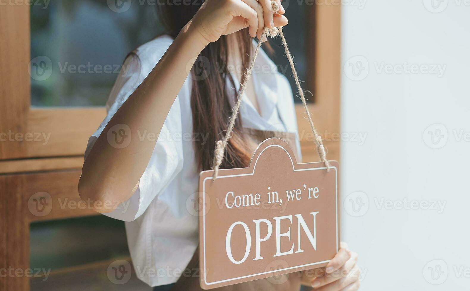 Welcome. Open. barista, waitress woman turning open sign board on glass door in modern cafe coffee shop ready to service, cafe restaurant, retail store, small business owner, food and drink concept photo