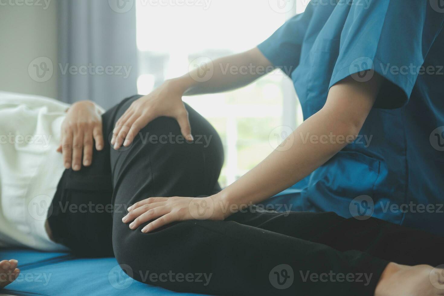 Happy senior woman doing exercise at home with physiotherapist. Old retired lady doing stretching arms at home with the help of a personal trainer during a rehabilitation session. photo
