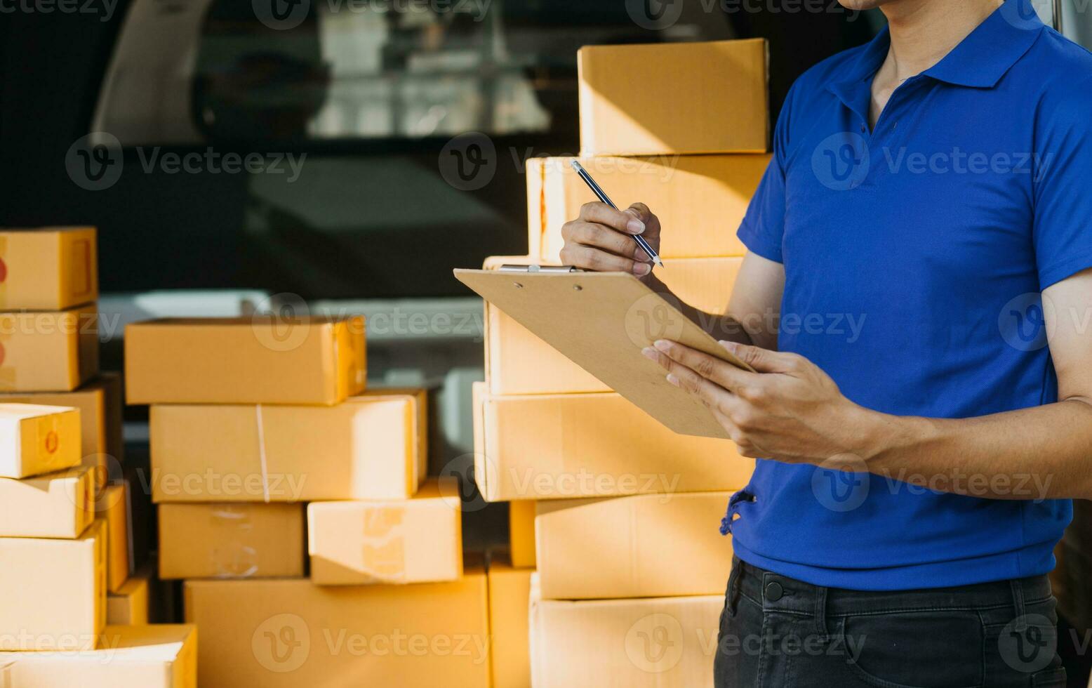 Delivery man with cardboard box checking document list In van and parcels on seat outside the warehouse. photo