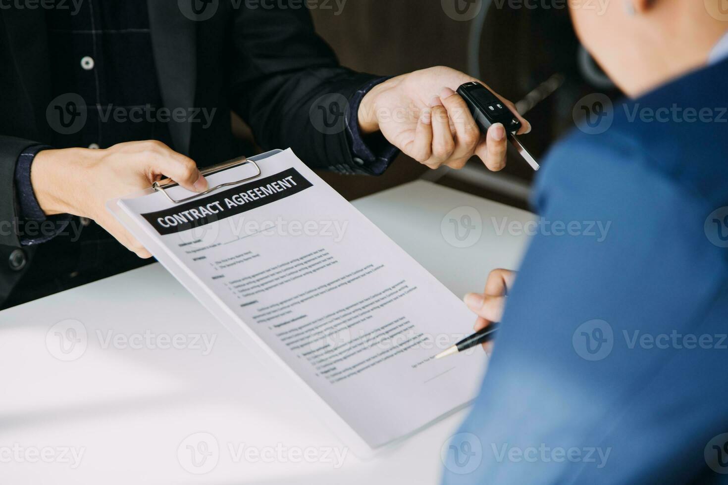 Hand holding car keys and car rental concept A close-up view of the agent, giving the customer the car keys after signing the lease, rental form and car name. photo