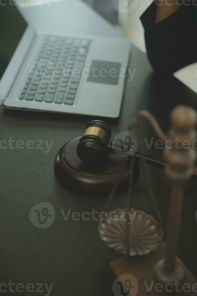 Justice and law concept.Male judge in a courtroom with the gavel, working with, computer and docking keyboard, eyeglasses, on table in morning light photo