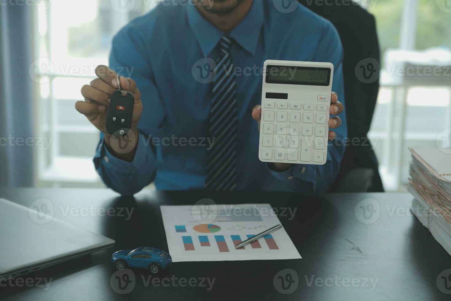 Man signing car insurance document or lease paper. Writing signature on contract or agreement. Buying or selling new or used vehicle. Car keys on table. Warranty or guarantee. Customer or salesman. photo