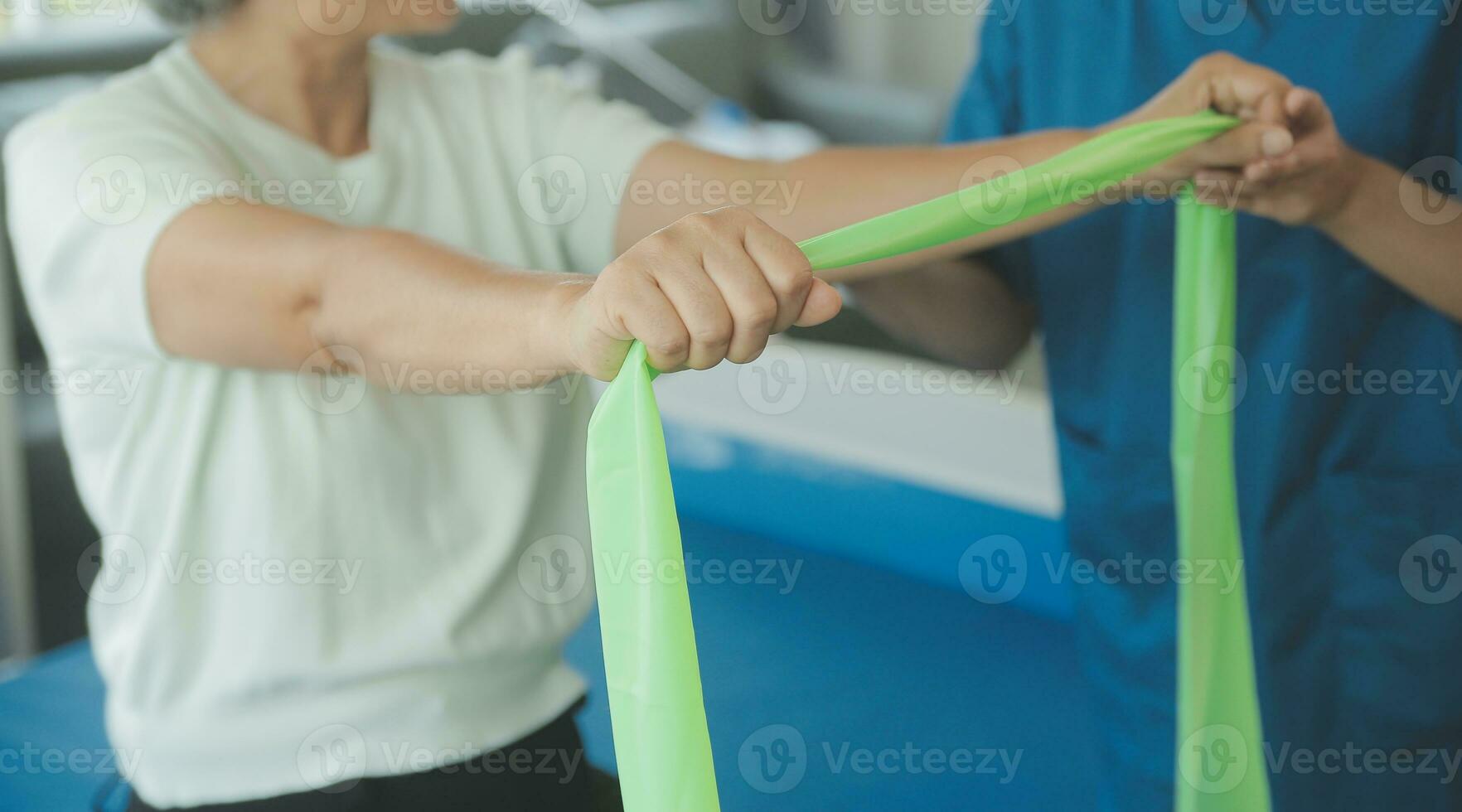 Doctor or nurse or physiotherapist caregiver exercise with senior woman at clinic or nursing home photo