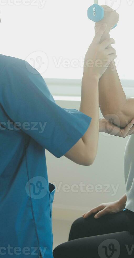 Physiotherapist man giving exercise with dumbbell treatment About Arm and Shoulder of athlete male patient Physical therapy concept photo