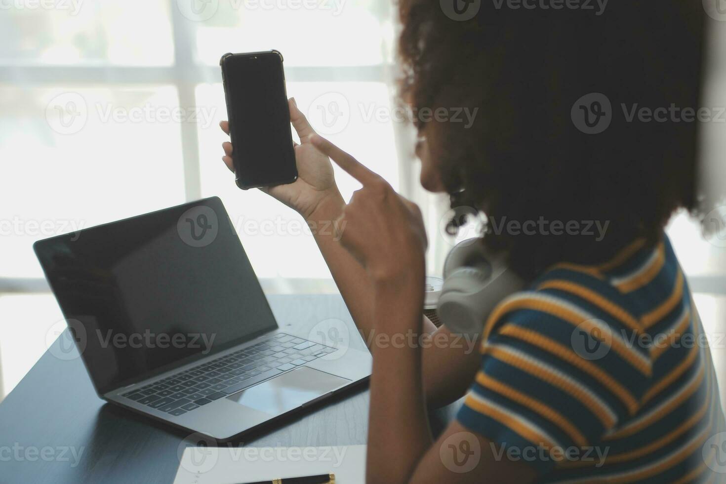 Young adult happy smiling Hispanic Asian student wearing headphones talking on online chat meeting using laptop in university campus or at virtual office. College female student learning remotely. photo