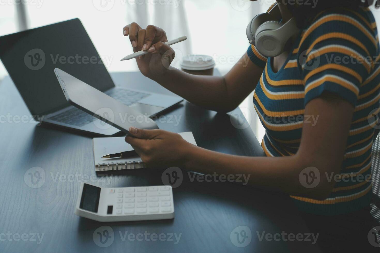 Young adult happy smiling Hispanic Asian student wearing headphones talking on online chat meeting using laptop in university campus or at virtual office. College female student learning remotely. photo