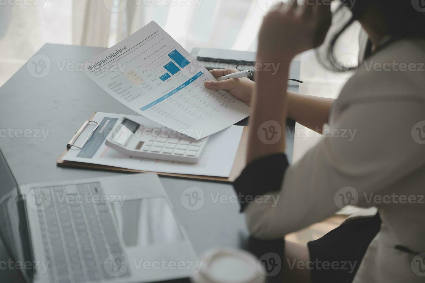 Asian Business woman using calculator and laptop for doing math finance on an office desk, tax, report, accounting, statistics, and analytical research concept photo