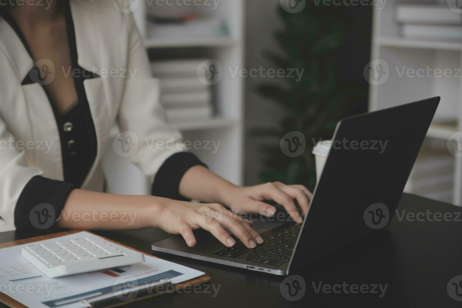 Asian Business woman using calculator and laptop for doing math finance on an office desk, tax, report, accounting, statistics, and analytical research concept photo