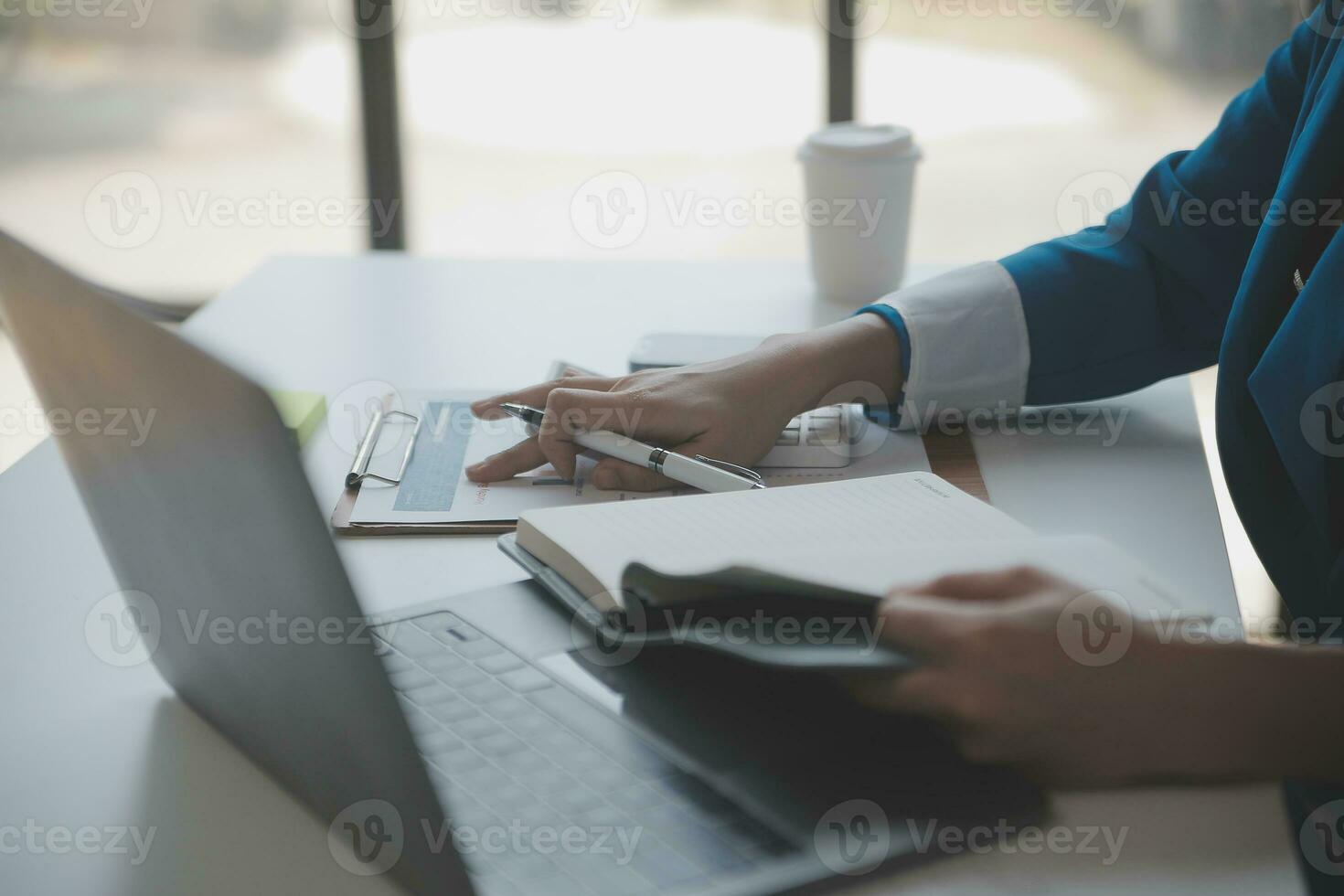 Asian Business woman using calculator and laptop for doing math finance on an office desk, tax, report, accounting, statistics, and analytical research concept photo