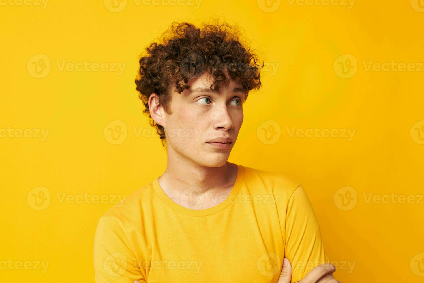 Young curly-haired man Youth style studio casual wear yellow background unaltered photo