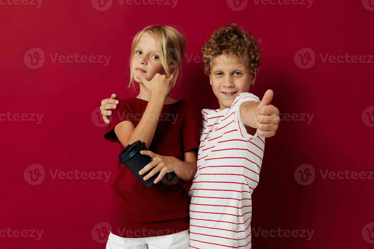 boy and girl disposable glass with drink posing red background photo