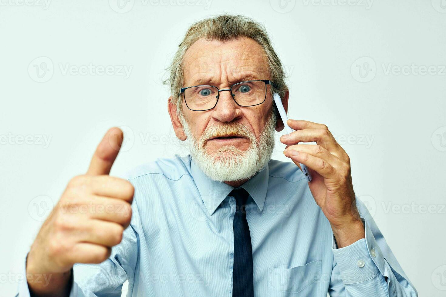 old man with phone in studio on white background shows thumb up photo