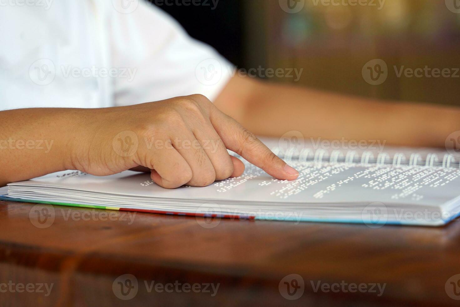 visualmente dañado persona lee con su dedos un libro escrito en braille eso es escrito para esos quien son visualmente dañado o ciego. eso es un especial código generado desde 6 6 puntos en el caja. foto