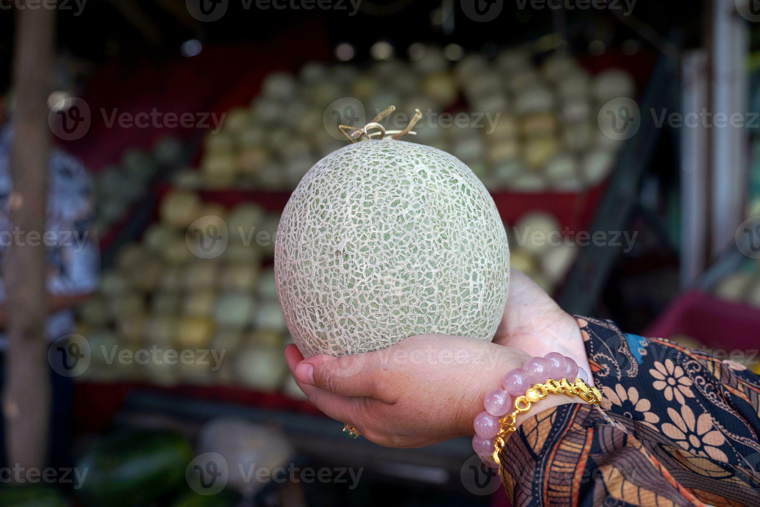 Asian female customers buy melons from street fruit stalls that sell
