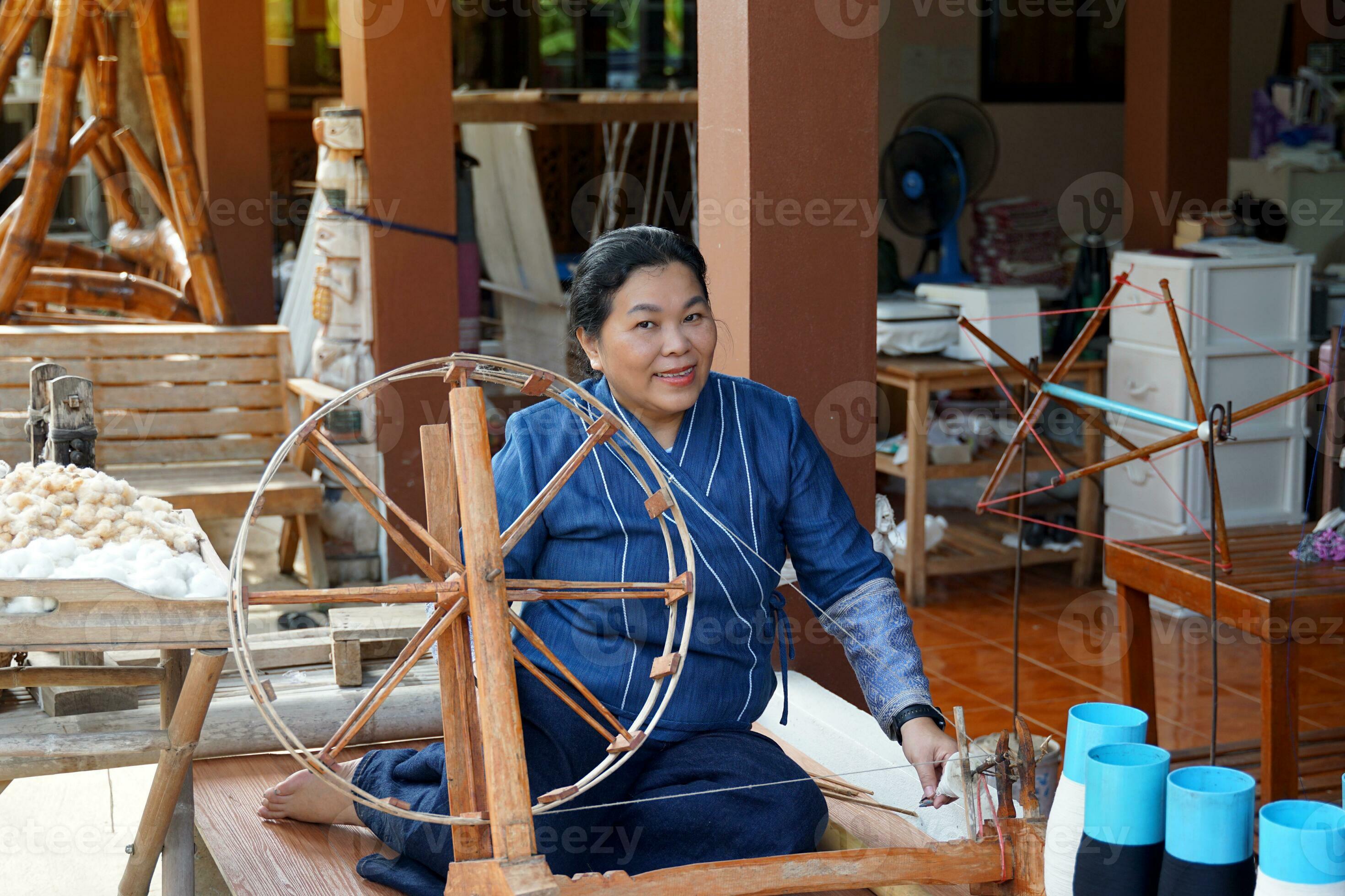 An Asian woman a member of a community hand weaving group spins An Asian woman a member of a community hand weaving group spins