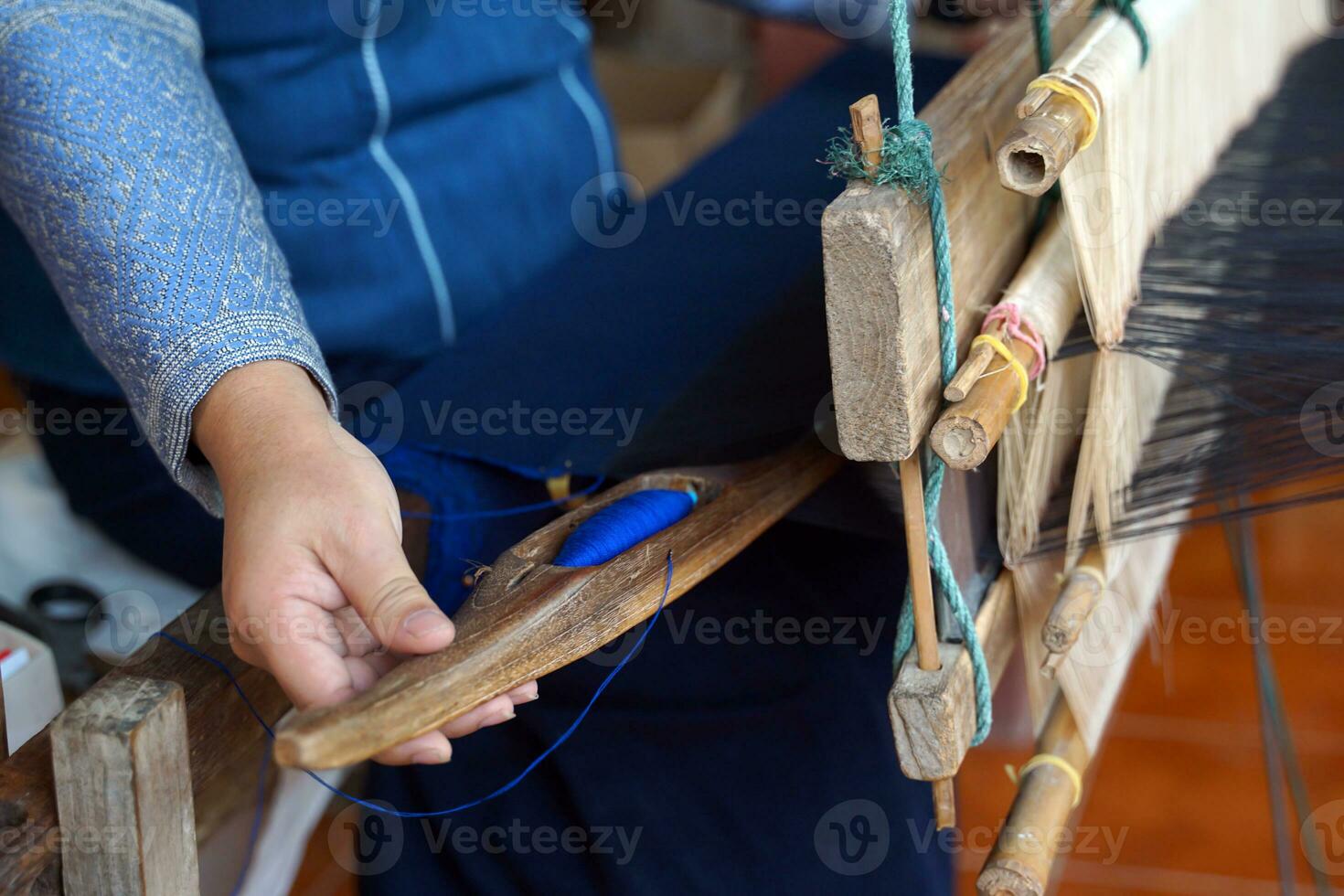 Asian female weavers weaving traditional patterns with hand weaving machines.in the concept of OTOP, community products, hand weaving fabrics, community shops, community weaving centers. photo