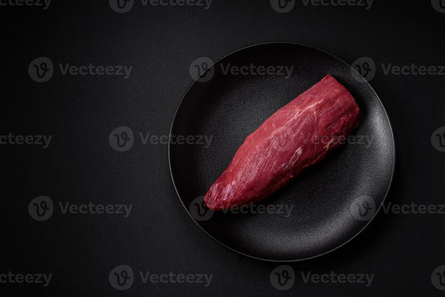 Juicy raw beef with spices, salt and herbs on a dark concrete background photo