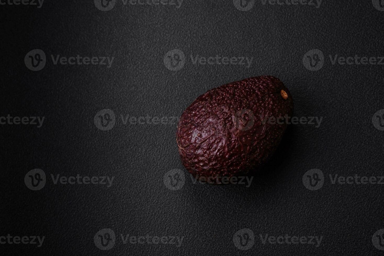 Fresh, ripe, soft brown colored avocado on a dark concrete background photo