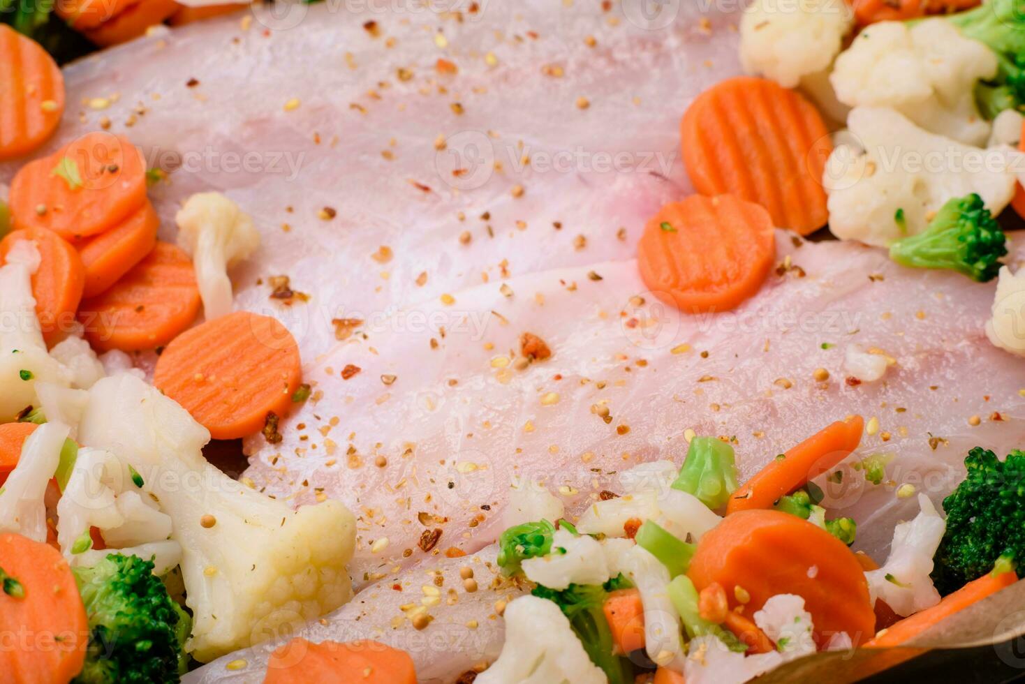 Raw sea bass fish fillet with salt, spices and vegetables in a baking dish photo