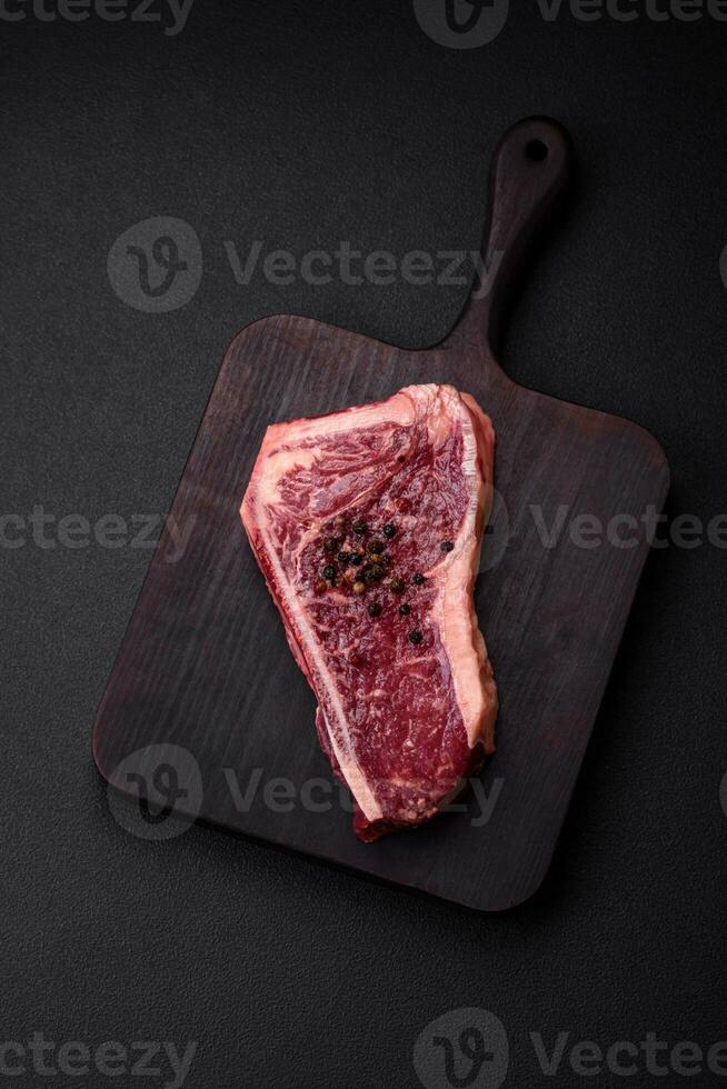 Fresco jugoso crudo nuevo York carne de vaca filete con sal, especias y hierbas foto