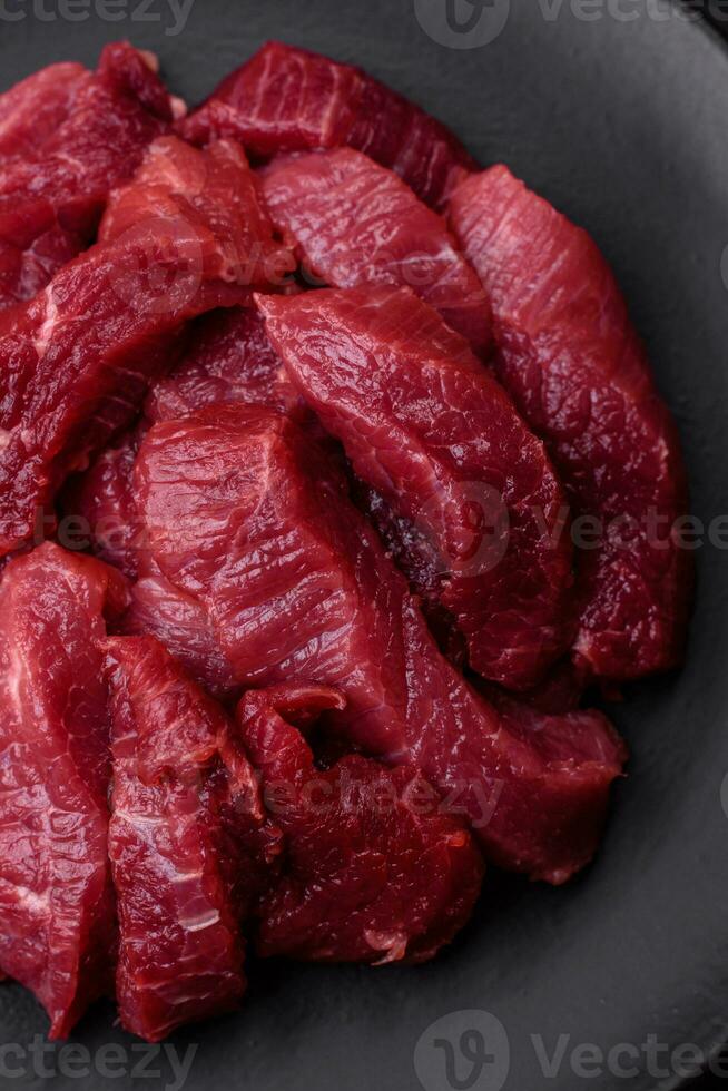 Juicy raw beef with spices, salt and herbs on a dark concrete background photo