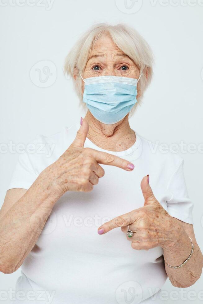 Photo of retired old lady in casual t-shirt and medical mask isolated background