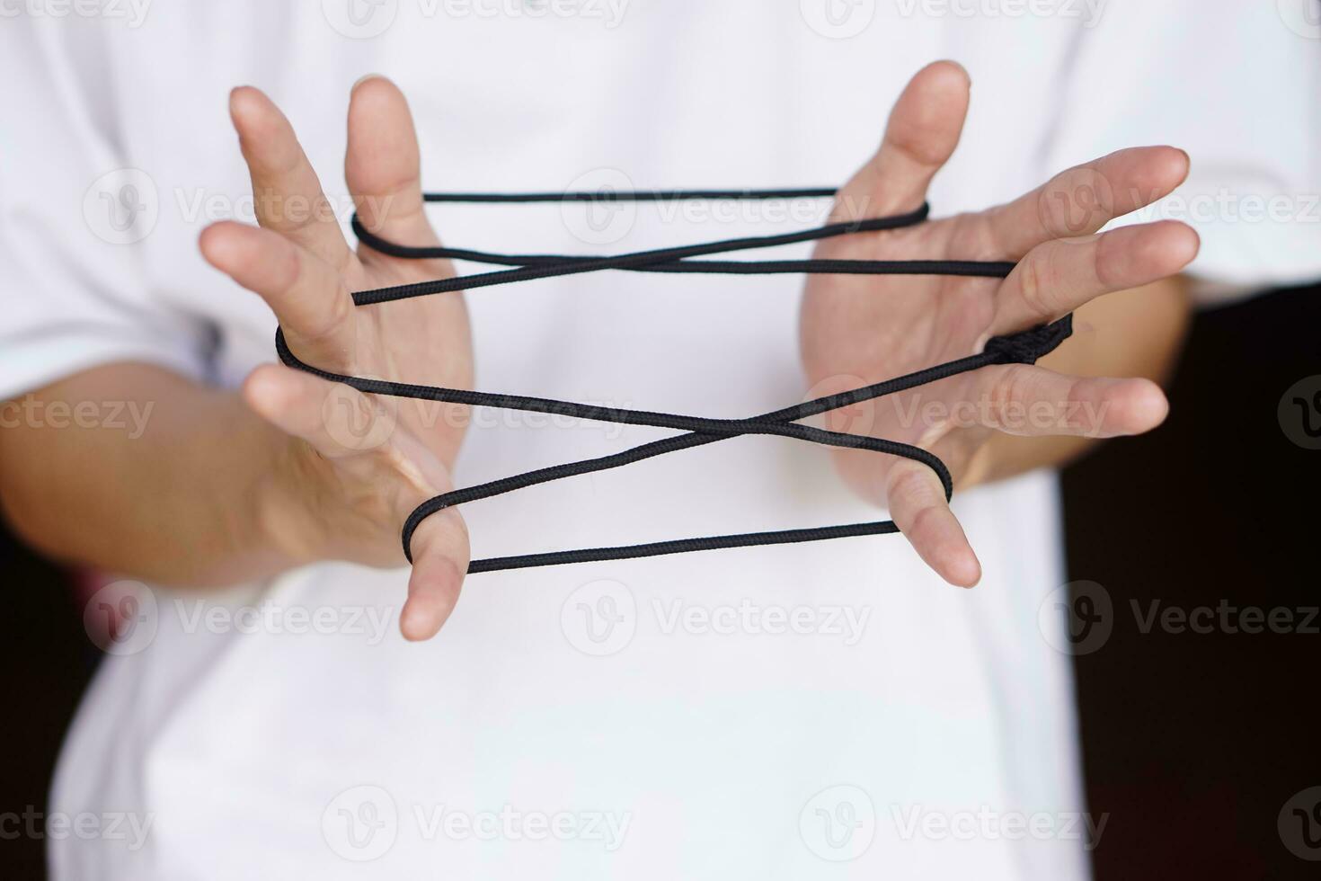 Closeup boy hands is playing rope which called cats cradle game. Concept, game involving the creation of various style figures between the fingers. Traditonal playing. photo