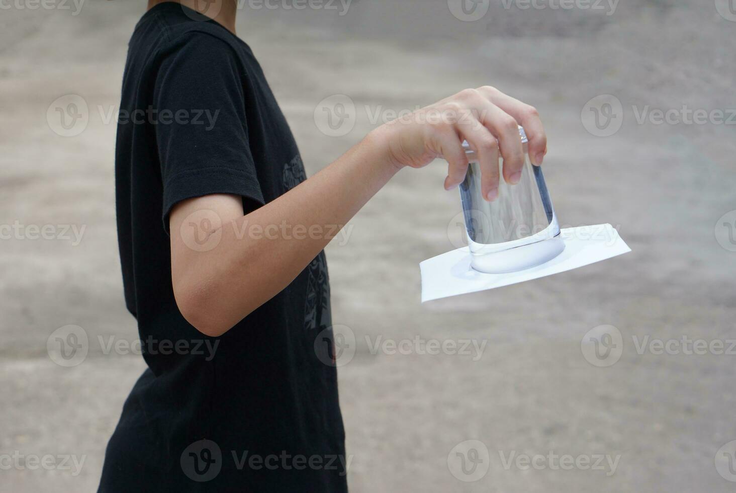 Closeup hand hold and turn a glass of water over down. covered the glass with paper. Concept, science experiment about air and liquid pressure. Easy science subject activity, education. photo