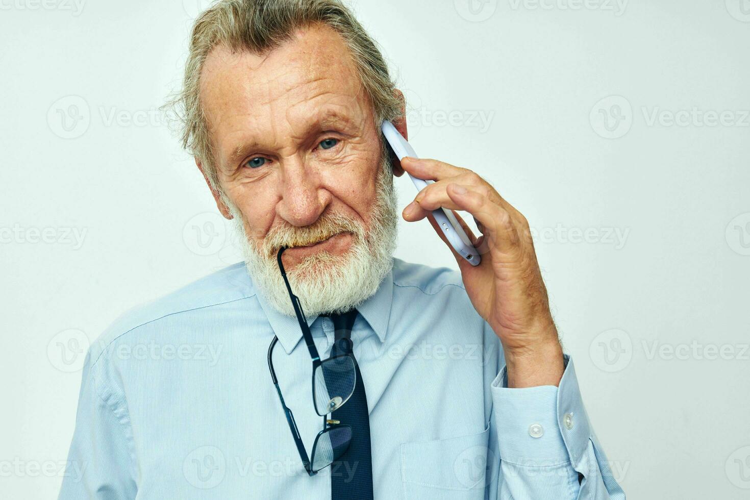 Photo of retired old man in a shirt with a tie with a phone technology light background