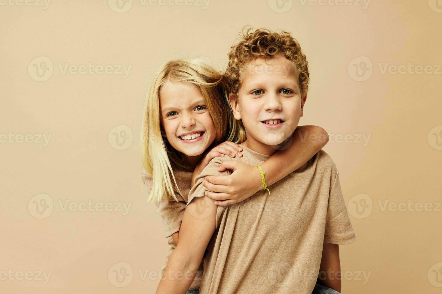 Portrait of cute children in beige t-shirts posing for fun isolated background photo