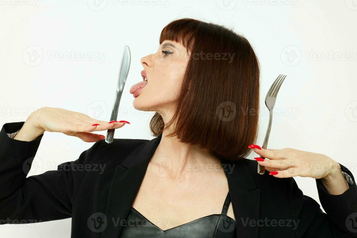 hermosa mujer en un negro chaqueta un cuchillo y un tenedor cerca el cara estilo de vida inalterado foto