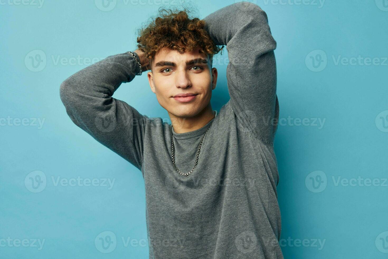 cute guy with curly hair posing blue background photo