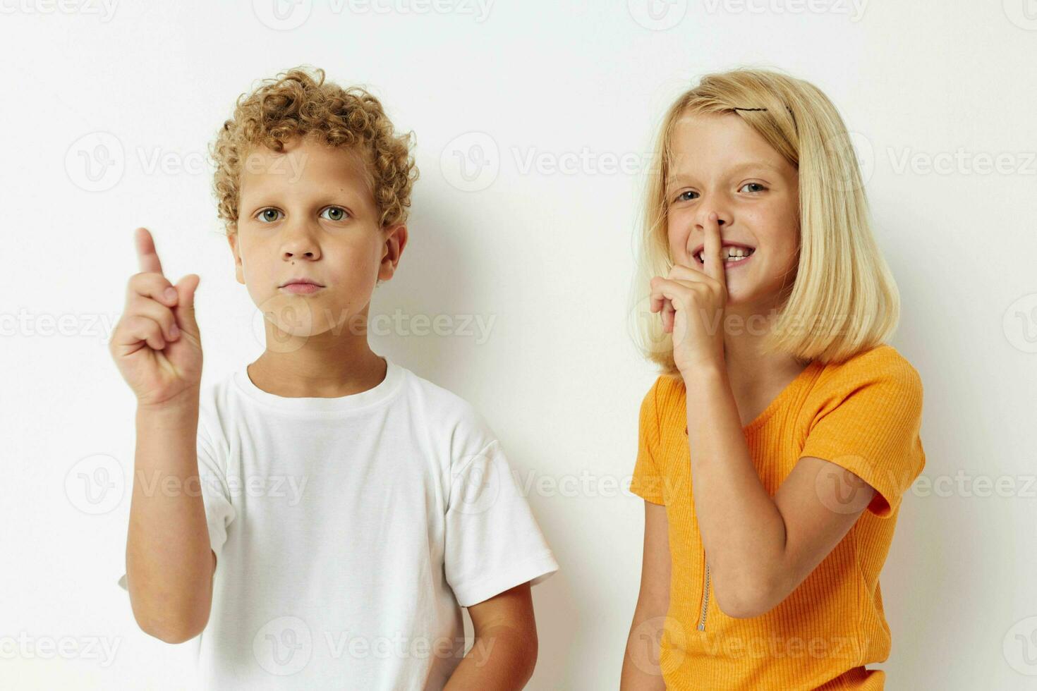 two joyful children posing hand gesture smile casual wear light background photo