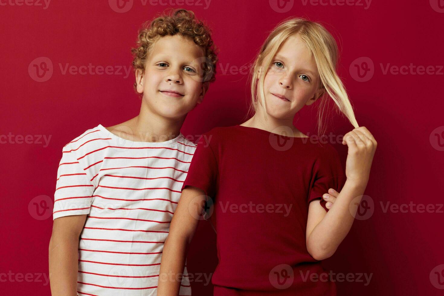 Small children good mood standing next to posing red background photo