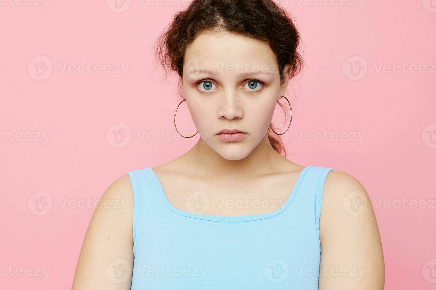pretty woman grimace close-up emotions earrings posing pink background unaltered photo