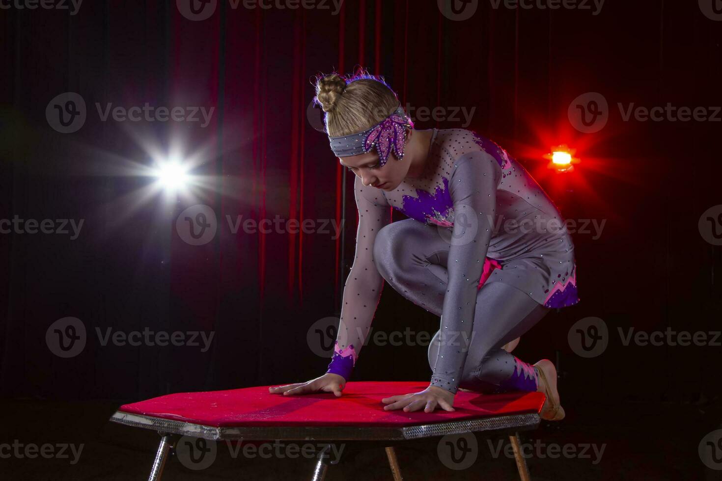 niña circo acróbata gimnasta en etapa en un oscuro antecedentes. foto