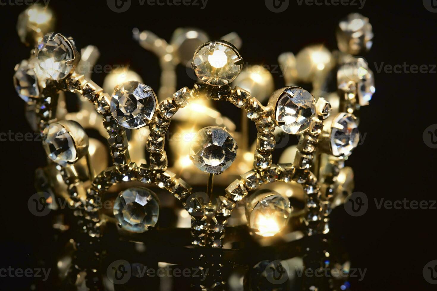 Gold crown with shiny stones on a black background. photo