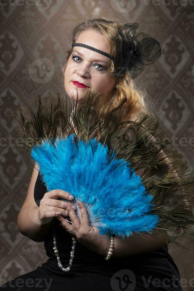 Retro portrait of an elderly woman in the style of 20s or 30s with a fan in her hands. photo