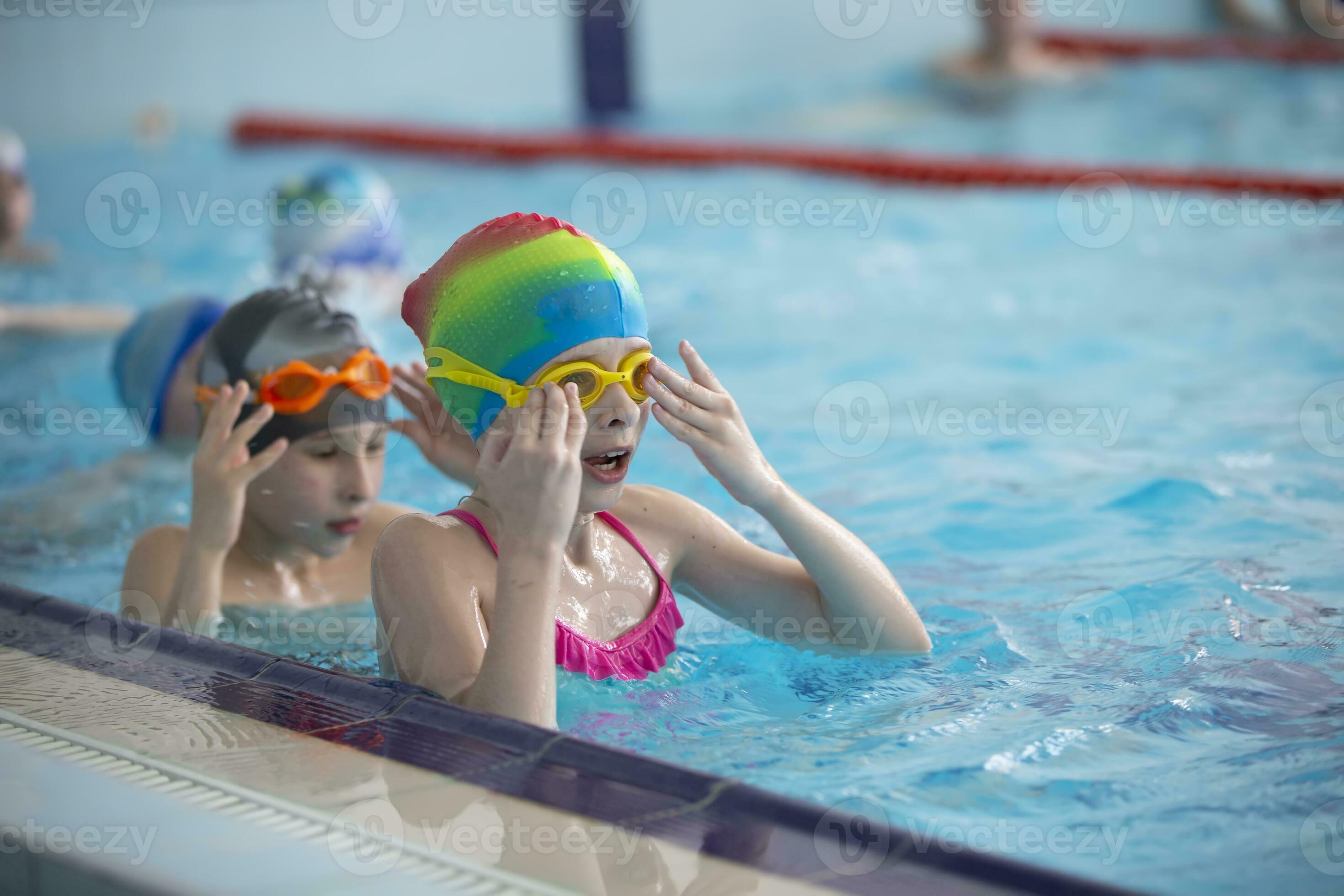 Boy in a swimming cap and swimming goggles in the pool. The child is
