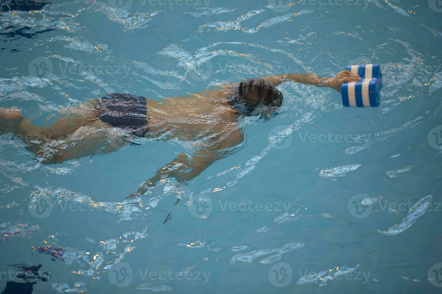 Boy in a swimming cap and swimming goggles in the pool. The child is engaged in the swimming section. photo