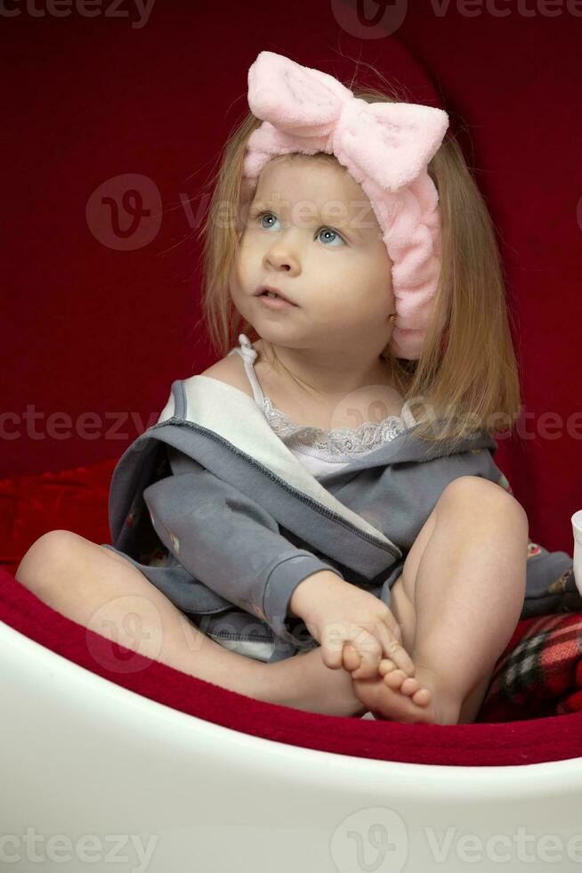 Two-year-old child. Little girl in home clothes on a red background. photo