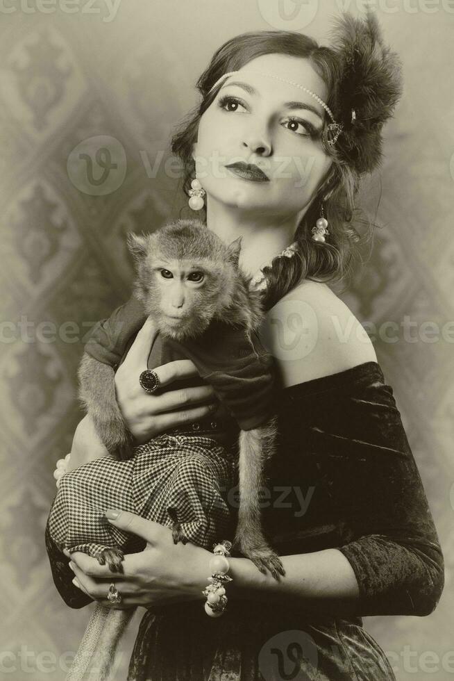 Retro female portrait in the style of 20s or 30s. A gorgeous lady is holding a little monkey. Photo in vintage style.