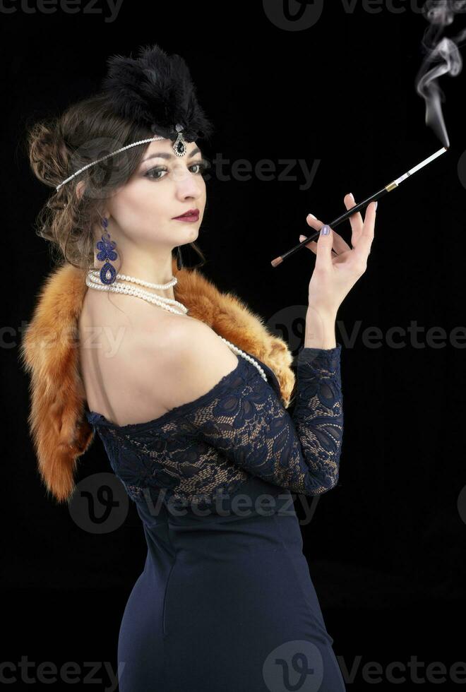 Retro woman portrait. A beautiful woman in the style of the 20s and 30s with a cigarette holder smokes. photo