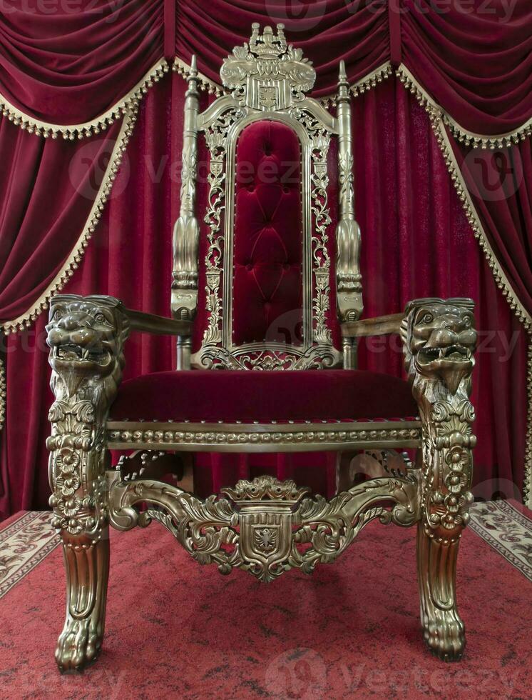 Red royal chair on a background of red curtains. Place for the king. Throne photo