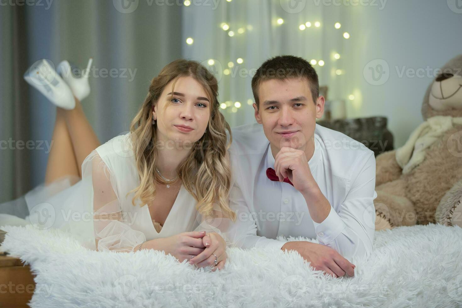 hermosa novia y novio mentira en el cama y Mira a el cámara. foto