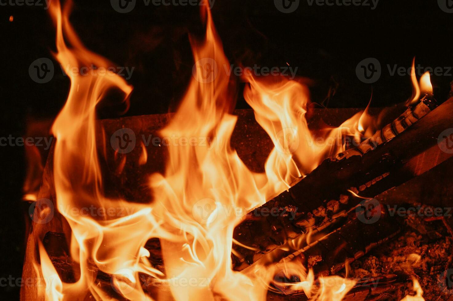 A bonfire in close-up, flames, charred pieces of logs and ashes in the open air. Camping. photo