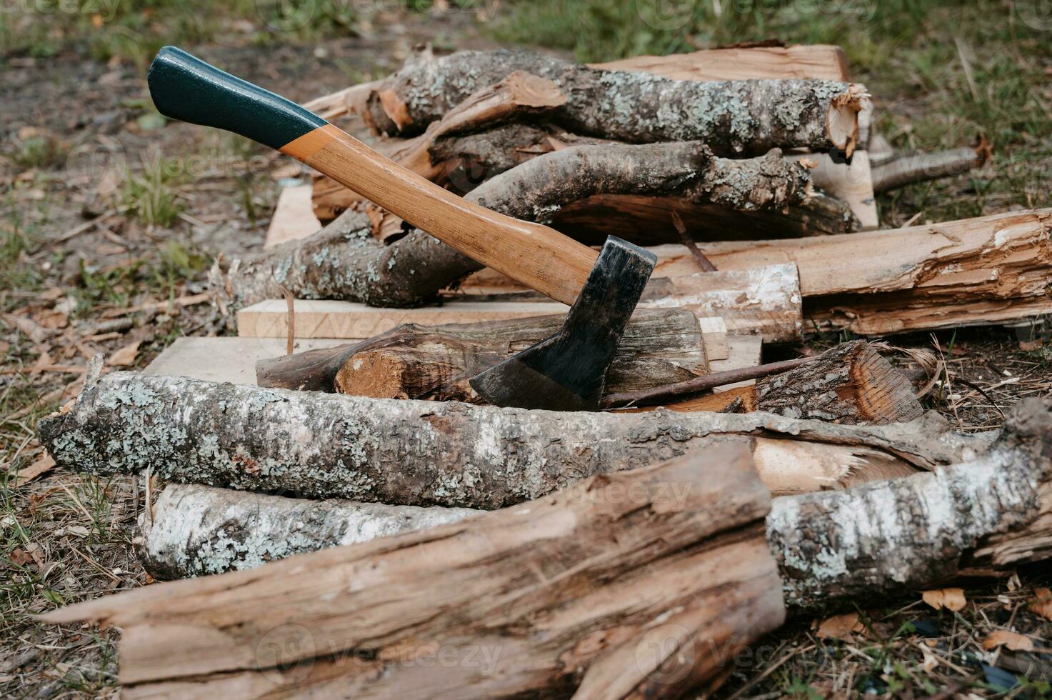An old battered axe is stuck in a log on a pile of firewood. Outdoor recreation. Preparation for the bonfire. photo