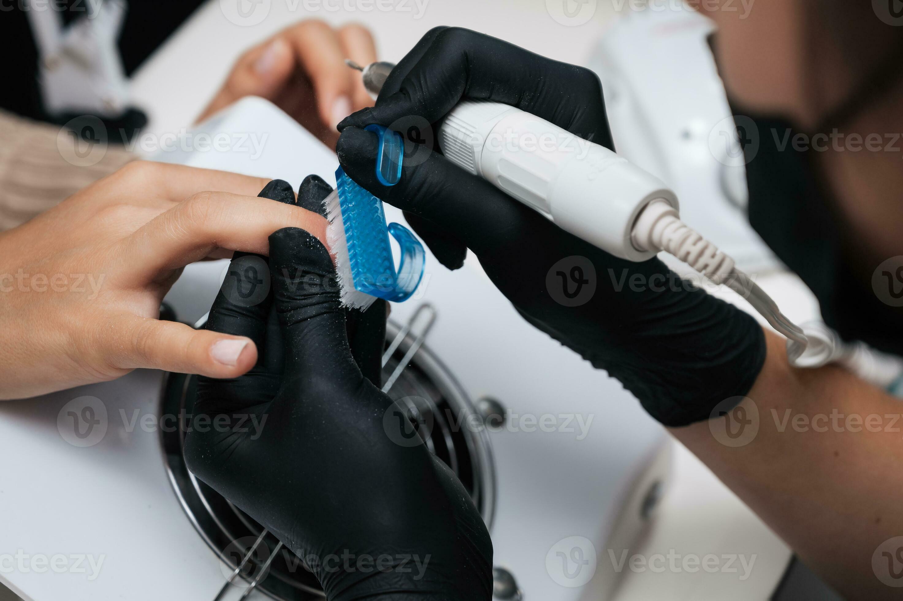 Hardware manicure. Closeup of a manicure master filing gel polish with