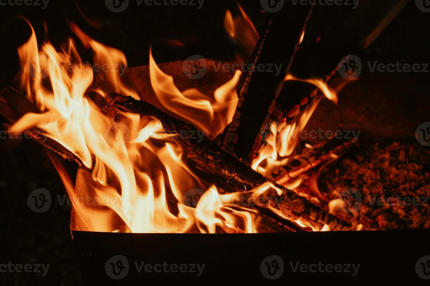 A bonfire in close-up, flames, charred pieces of logs and ashes in the open air. Camping. photo